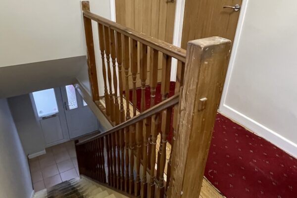 Staircase and landing renovation in Rugby featuring bespoke clad posts, increased handrail height, and toughened glass balustrade panels set into grooves. A modern and safer staircase transformation by Robert McVey Staircases.
