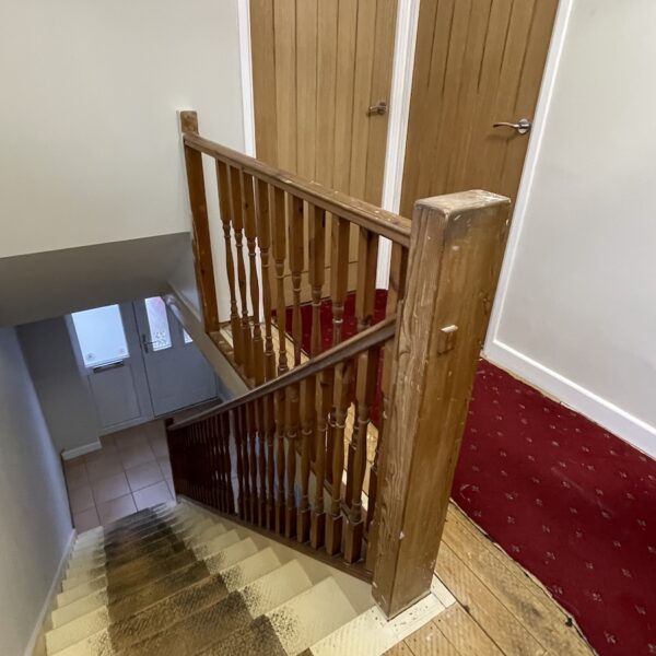Staircase and landing renovation in Rugby featuring bespoke clad posts, increased handrail height, and toughened glass balustrade panels set into grooves. A modern and safer staircase transformation by Robert McVey Staircases.