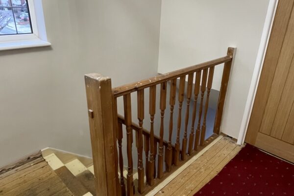 Staircase and landing renovation in Rugby featuring bespoke clad posts, increased handrail height, and toughened glass balustrade panels set into grooves. A modern and safer staircase transformation by Robert McVey Staircases.