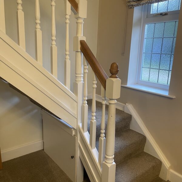 Open tread staircase renovation in Burbage featuring bespoke oak newel posts, modern twist metal spindles, and custom under-stair doors. A stylish upgrade completed in just two days by Robert McVey Staircases.