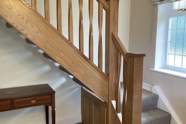 Open tread staircase renovation in Burbage featuring bespoke oak newel posts, modern twist metal spindles, and custom under-stair doors. A stylish upgrade completed in just two days by Robert McVey Staircases.