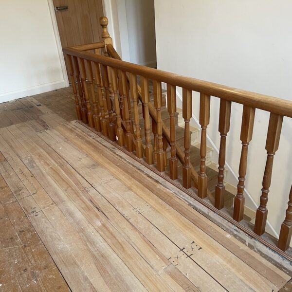 Staircase renovation in Broughton Astley featuring American white oak components with a clear oil finish and glass balustrade panels mounted on chrome brackets. A bright, modern hallway transformation completed in two days by Robert McVey Staircases.